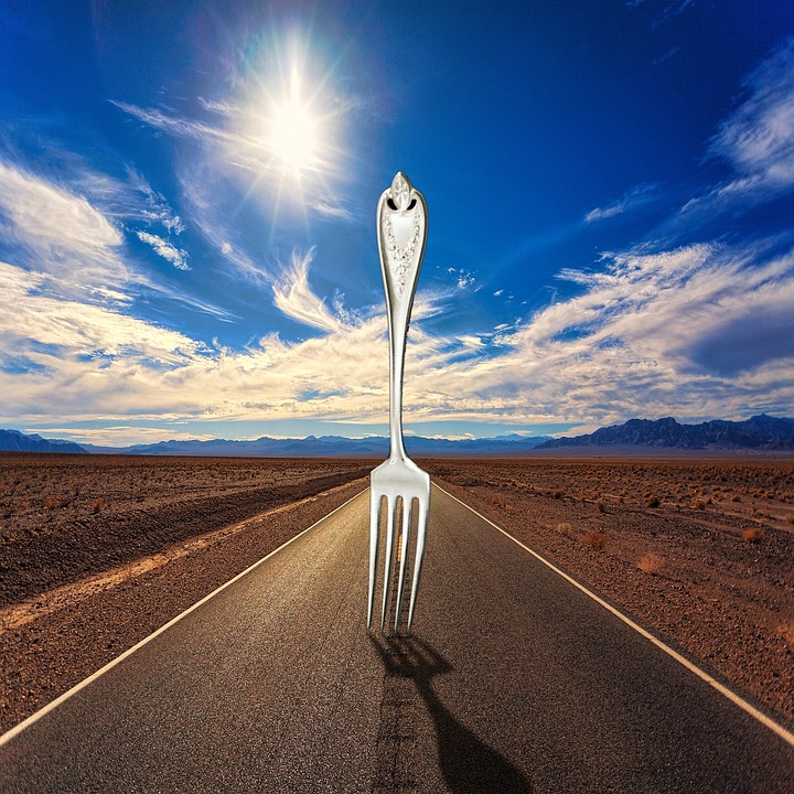 an illustration of a large dinner fork stuck upright into a road