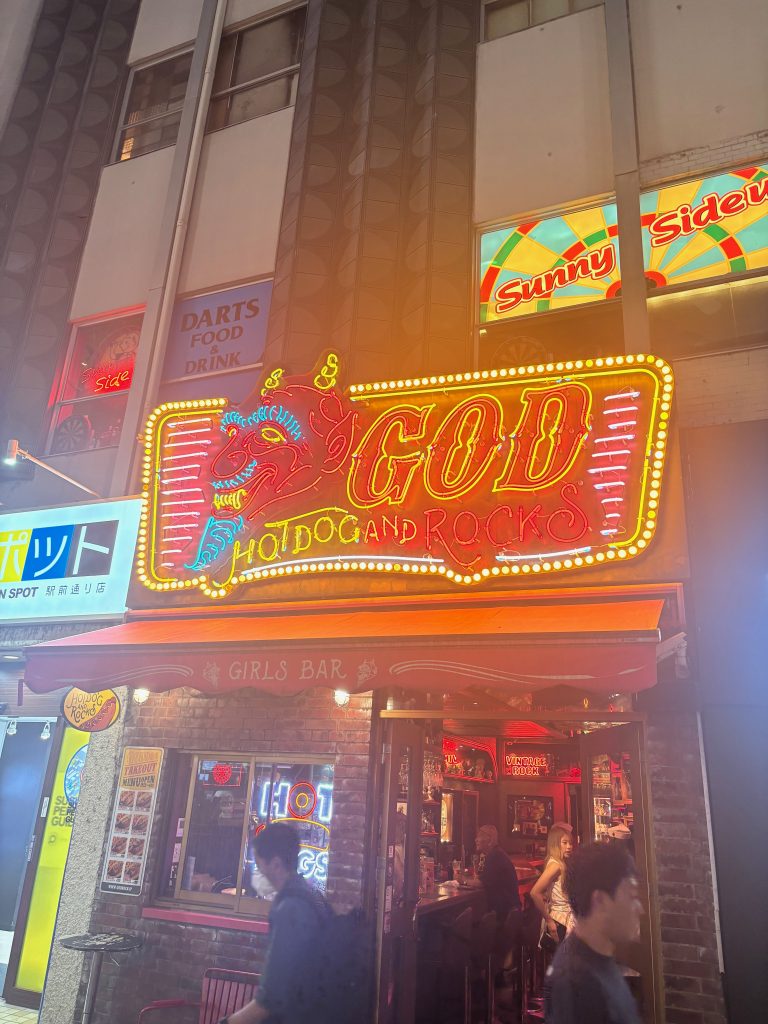Neon sign: God Hotdogs and Rocks, with a cartoon devil logo, in Sapporo, Japan